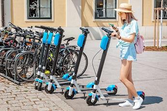 Asian woman renting electric kick scooter at city street. Modern sharing urban transport concept